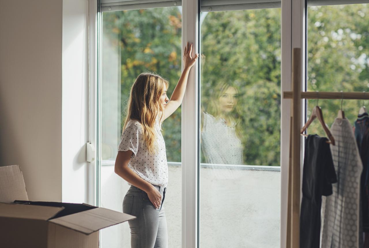 Junge Frau steht am Fenster